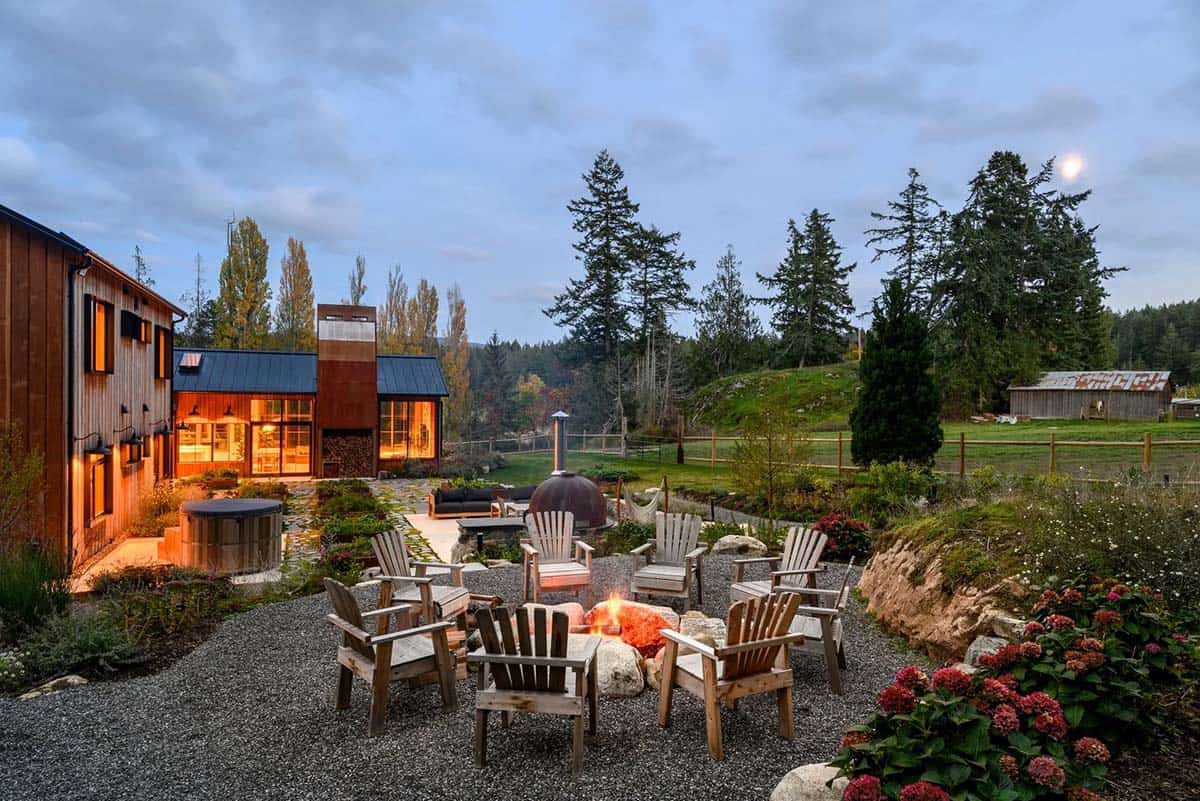 Outdoor fireplace with wood storage in a rustic backyard setting.