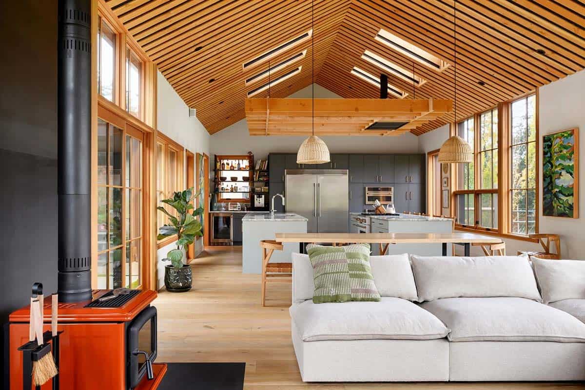 Bright modern farmhouse living room with high vaulted wooden ceiling and large windows.