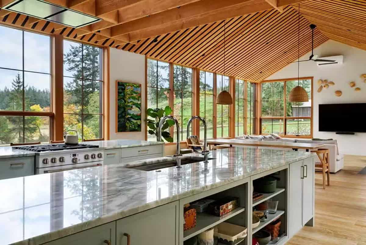 Bright modern farmhouse kitchen with large windows and wooden ceiling.