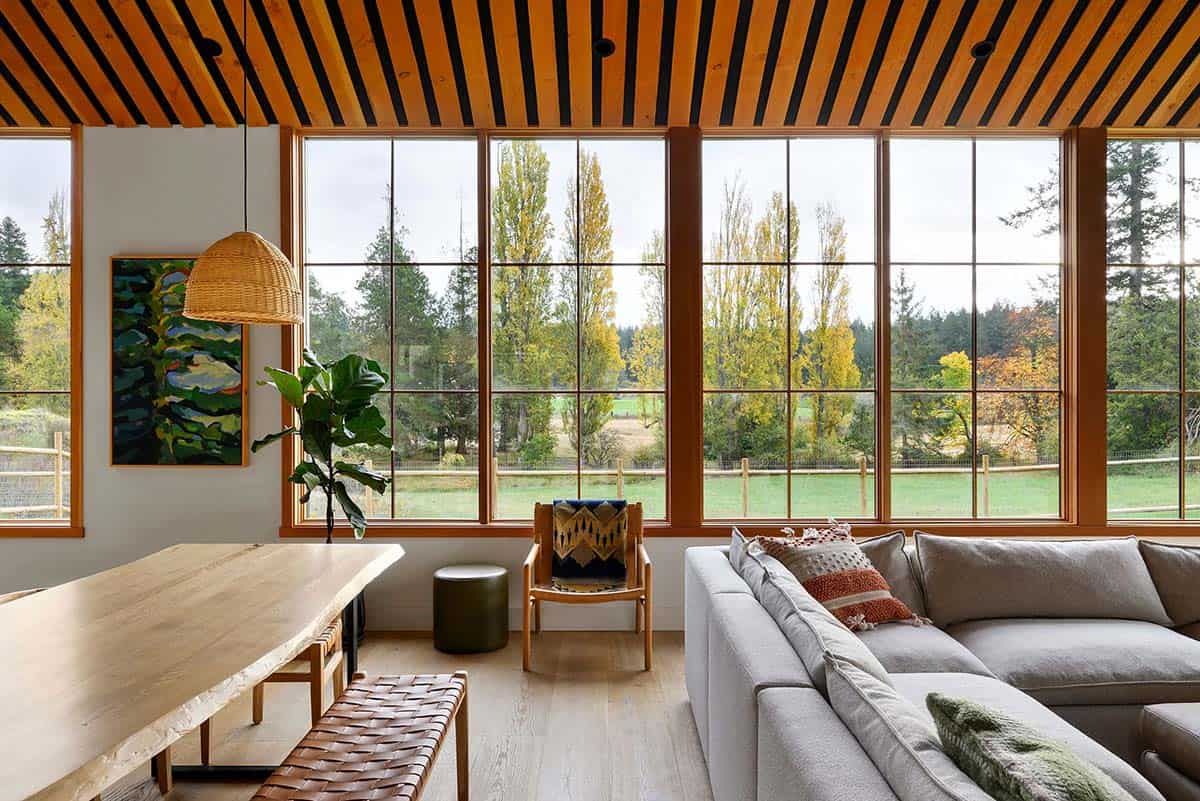 Bright interior of a modern farmhouse family home with large windows overlooking nature.