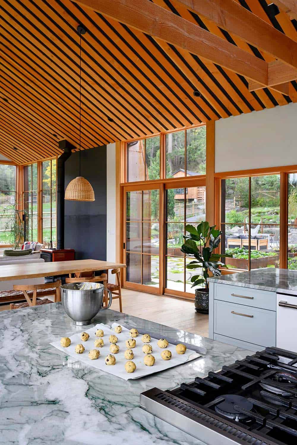 Modern farmhouse kitchen with wooden ceiling and large windows.