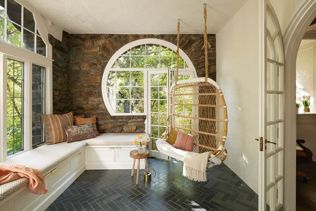 modern sunroom with a hanging chair and built-in window seat