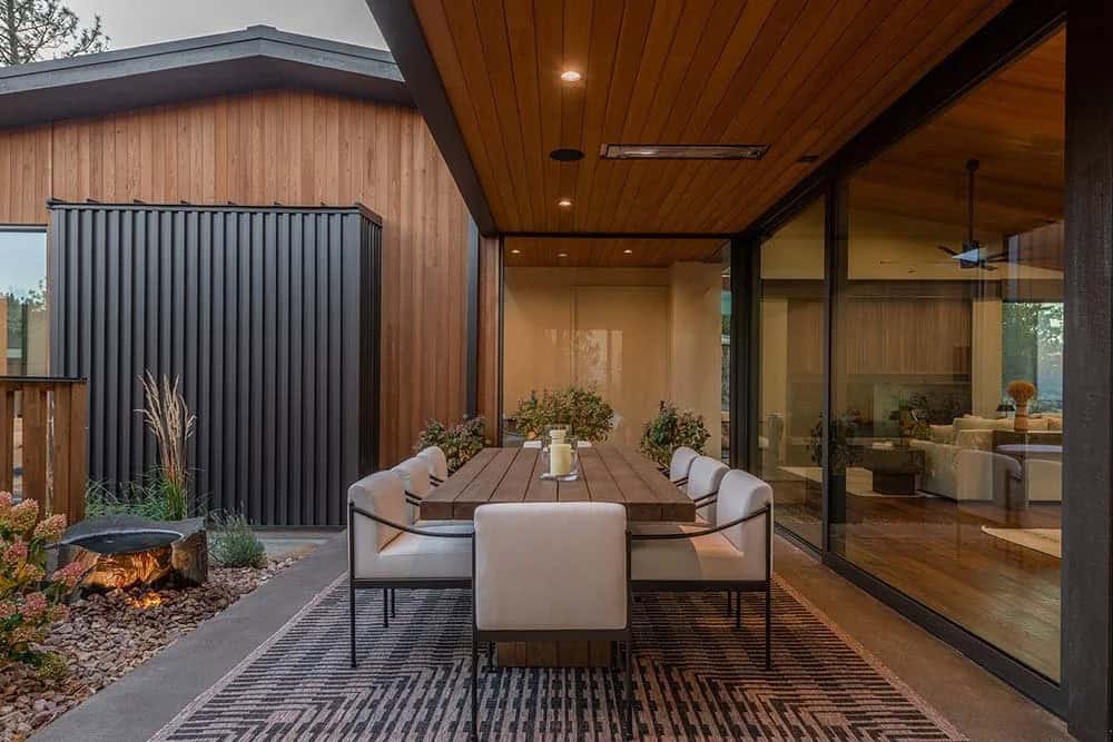 modern house exterior with a patio and outdoor dining at dusk