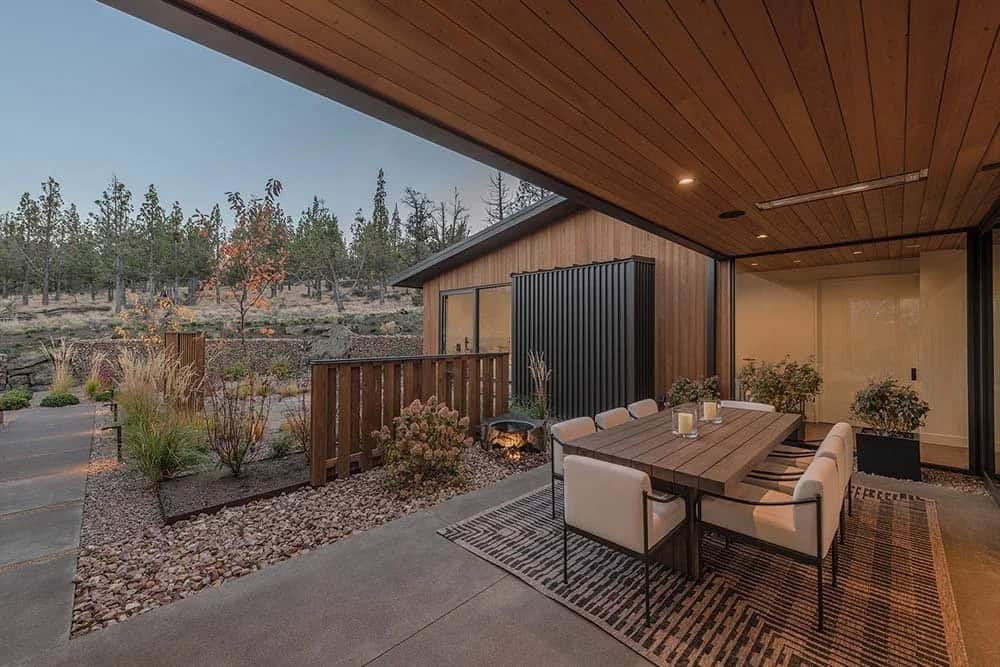 modern house exterior with a patio and outdoor dining at dusk