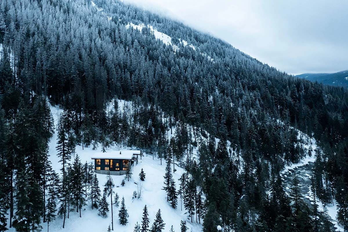 off-grid mountain cabin exterior with snow at dusk