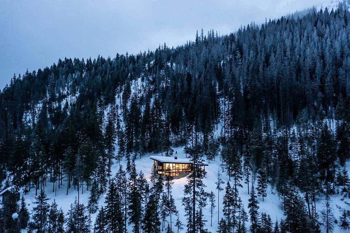 off-grid mountain cabin exterior with snow at dusk