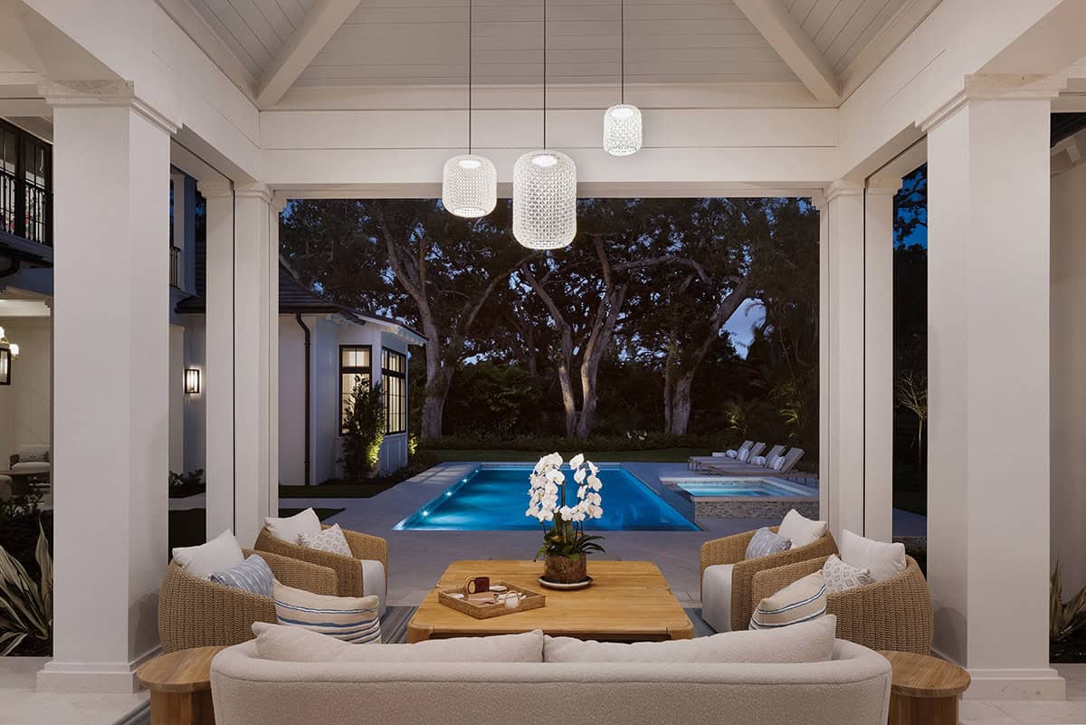 coastal style covered patio with a view of the pool at dusk