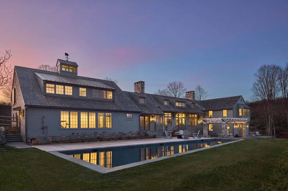 Saltbox Farm house exterior with a pool at dusk