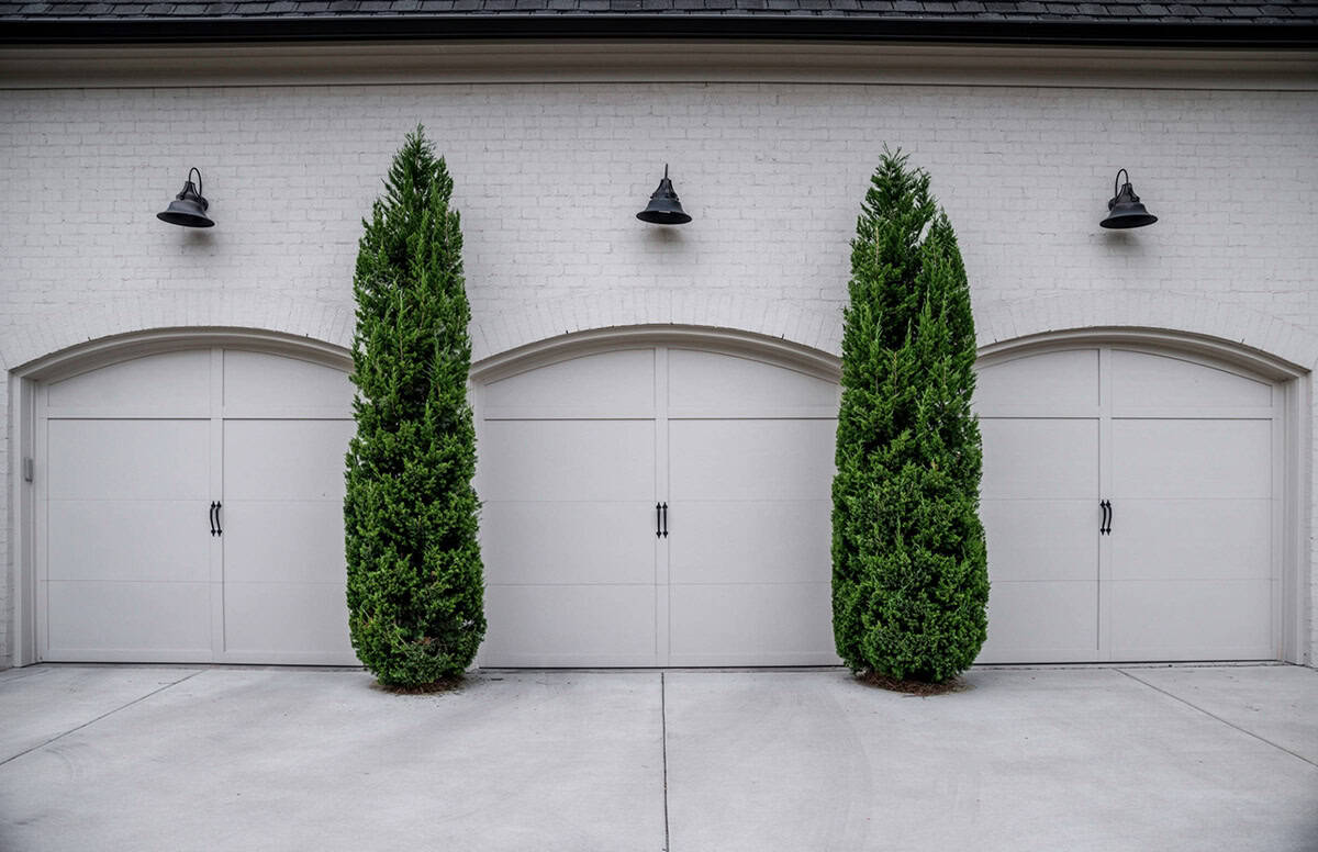 French Country home exterior garage view with carriage-style doors and manicured landscaping, Nashville Tennessee