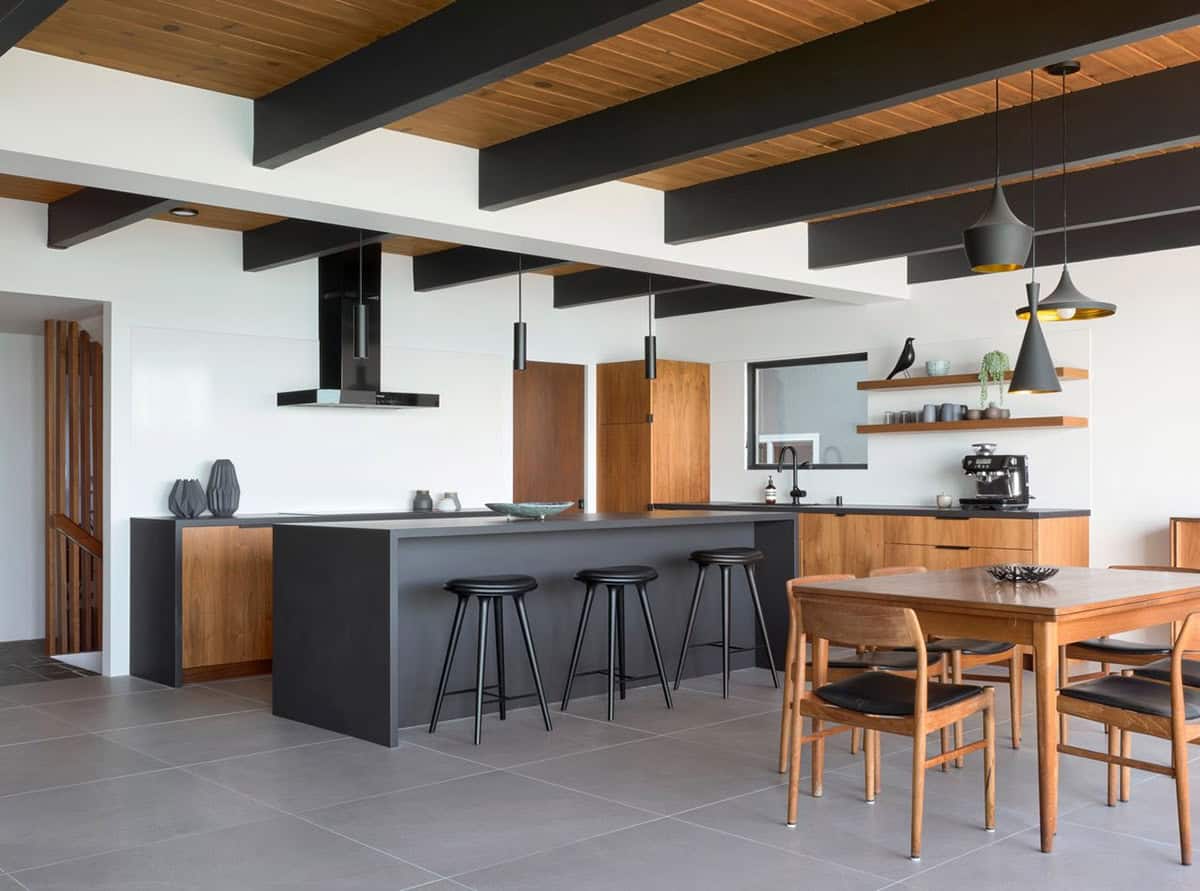 renovated midcentury modern kitchen with black island teak cabinetry open shelving and Tom Dixon pendants San Francisco Bay home