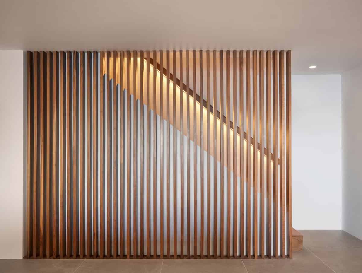floor to ceiling walnut slat stair wall with warm LED strip lighting midcentury modern family home Klopf Architecture