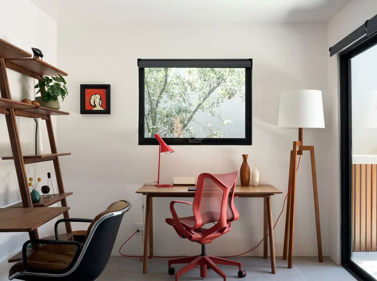 midcentury modern home office with red Herman Miller Cosm chair walnut leaning shelving red AJ table lamp and garden window