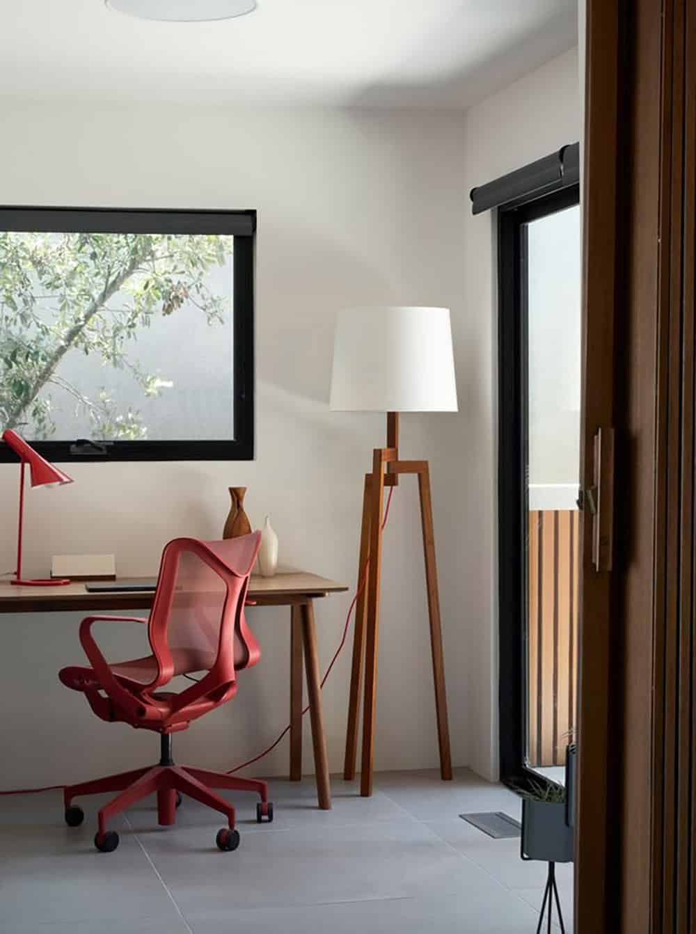 midcentury modern home office with red task chair walnut tripod floor lamp and sliding glass door to balcony