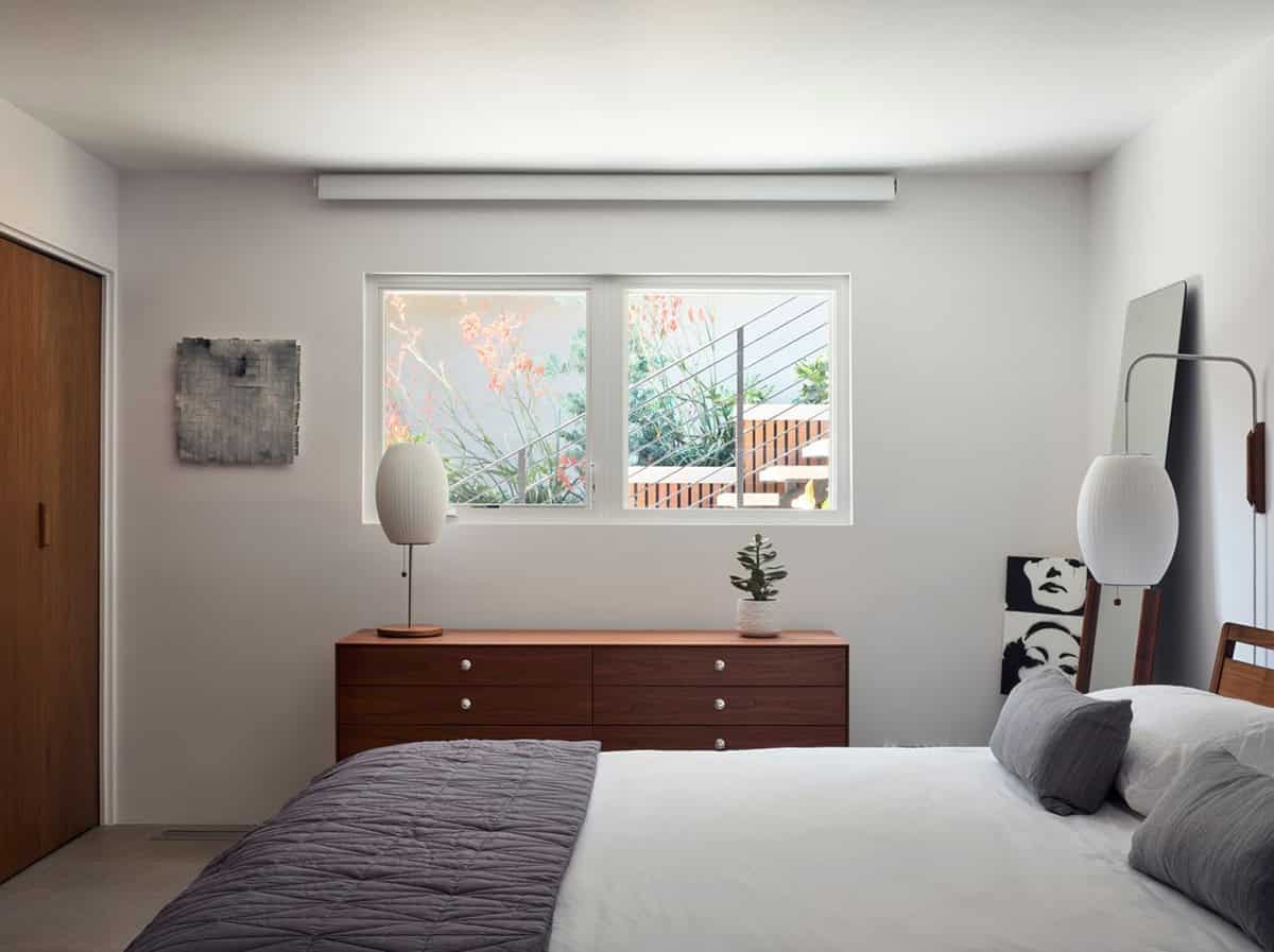 midcentury modern guest bedroom with walnut dresser Nelson bubble lamps gray bedding and garden window