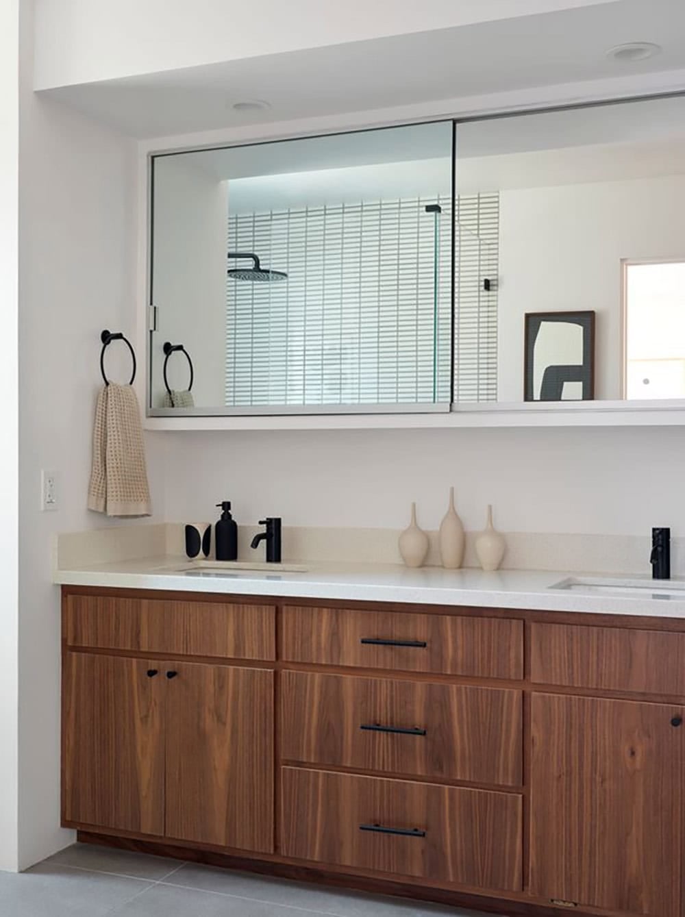 midcentury modern primary bathroom with walnut double vanity white quartz countertop matte black faucets and wide mirror