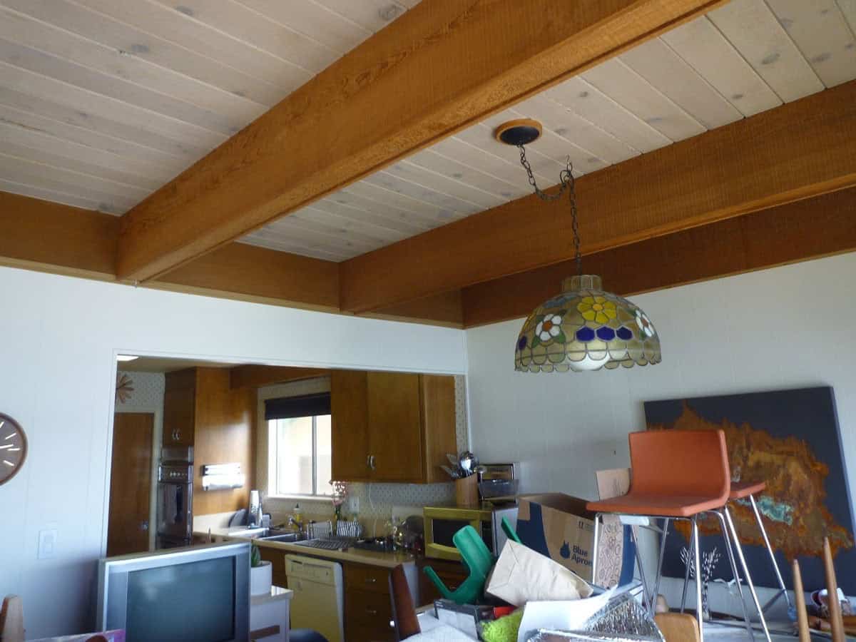 before renovation interior of midcentury modern home with original wood beam ceiling dated kitchen and stained glass pendant light Point Richmond California