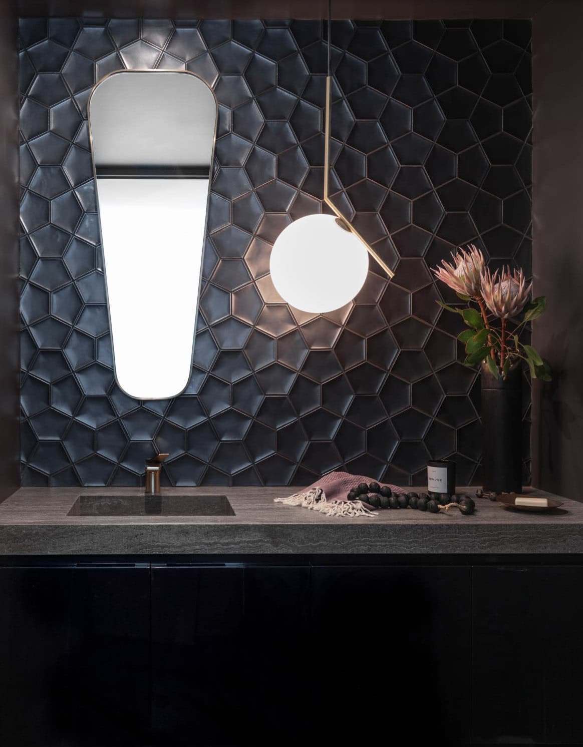 Dark geometric tile powder room with gold mirror and globe pendant light