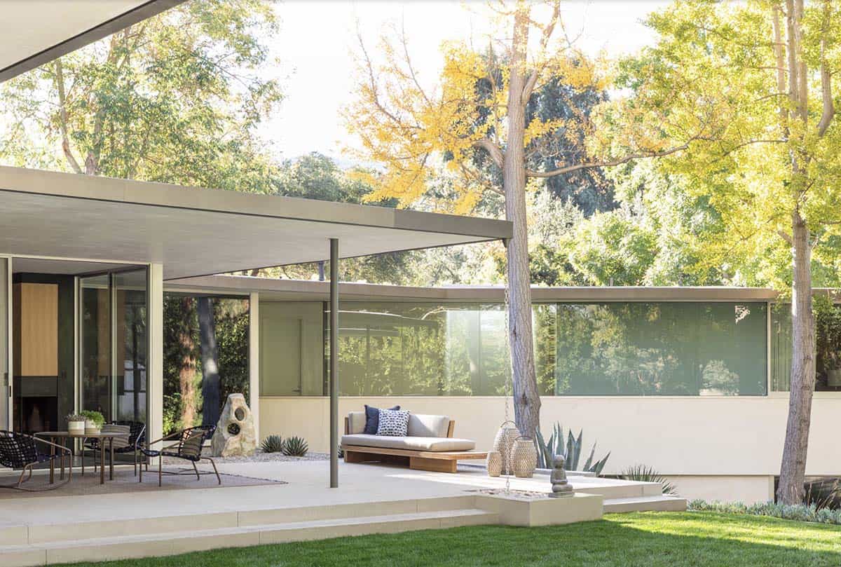 Covered outdoor patio with teak daybed and flat-roof mid-century modern home