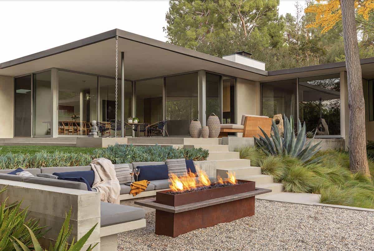 Lit outdoor fire pit with sectional seating facing mid-century glass facade