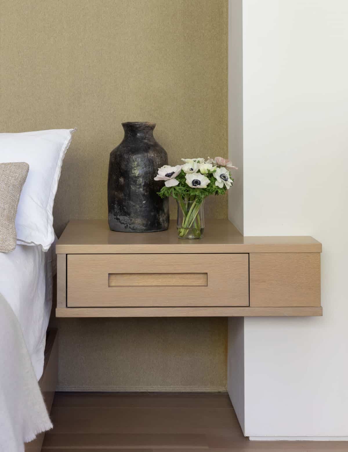 Floating oak nightstand with dark ceramic vase and white anemone flowers