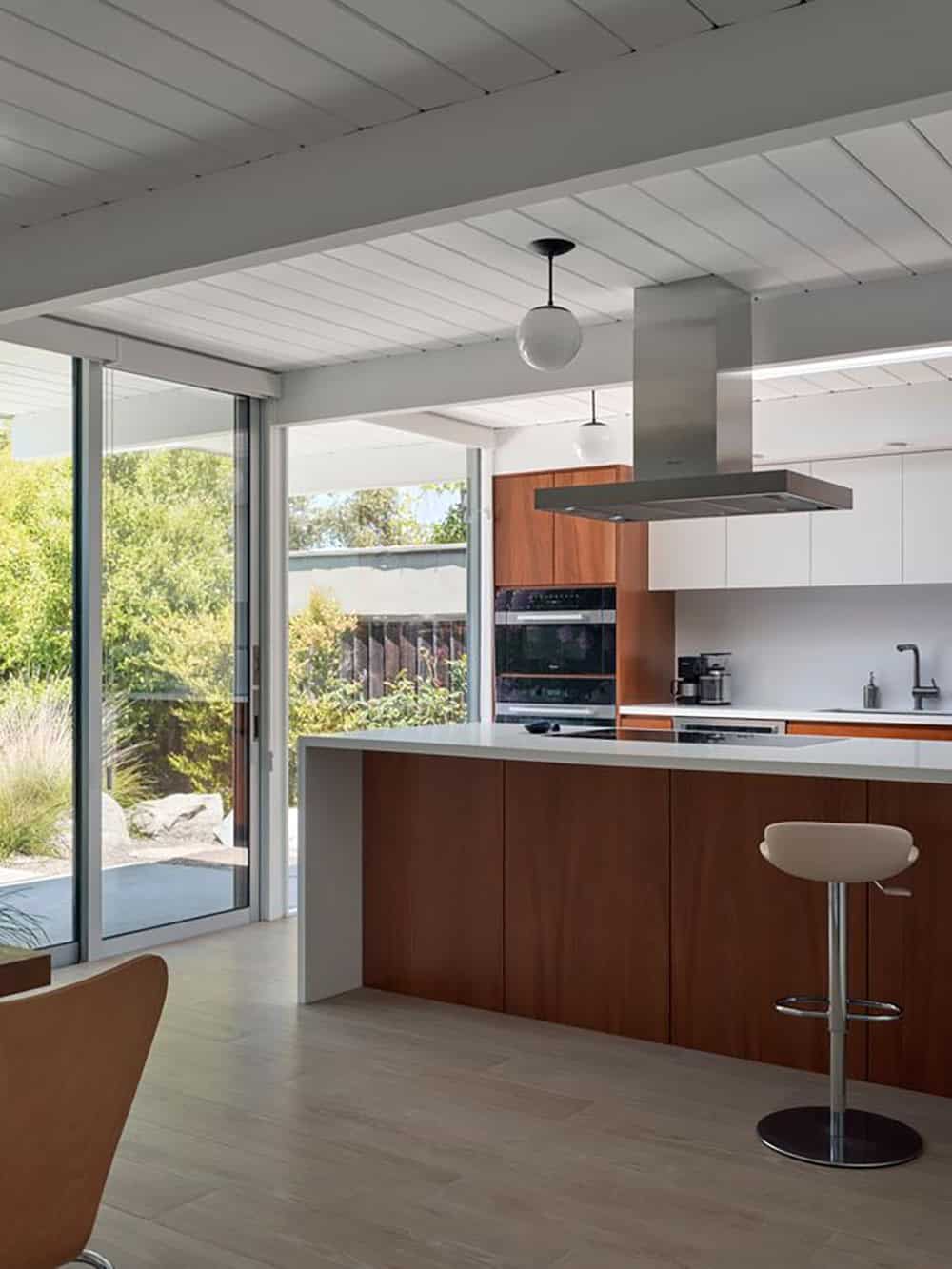 renovated Eichler kitchen with walnut cabinetry white countertops and sliding glass door opening to garden Sunnyvale California
