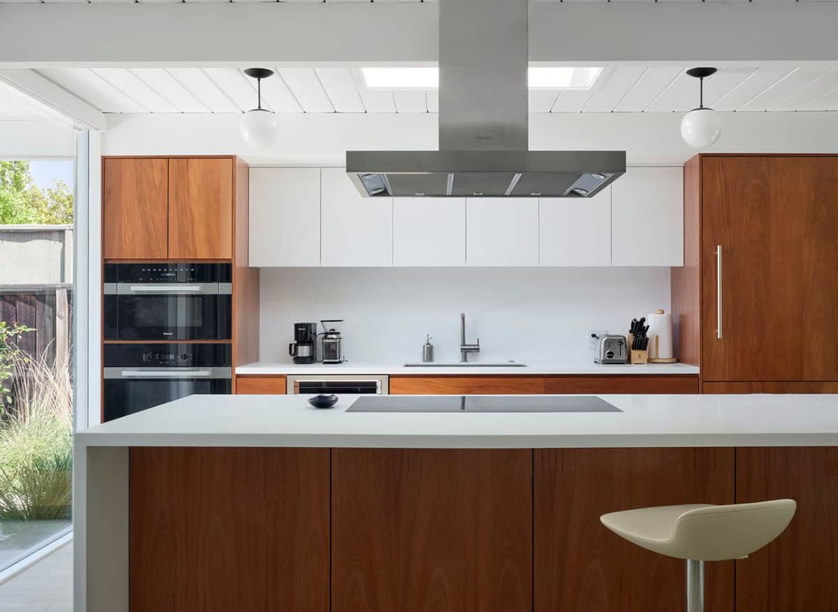 mid-century modern kitchen remodel with walnut cabinets stainless range hood skylights and globe pendants Klopf Architecture