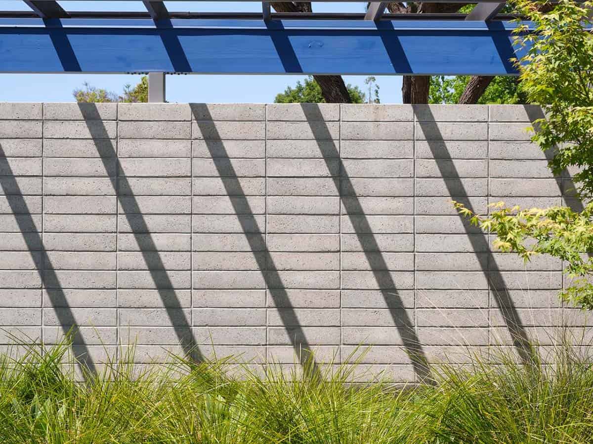 concrete block privacy wall with steel pergola casting diagonal shadows in mid-century modern Eichler landscape Sunnyvale