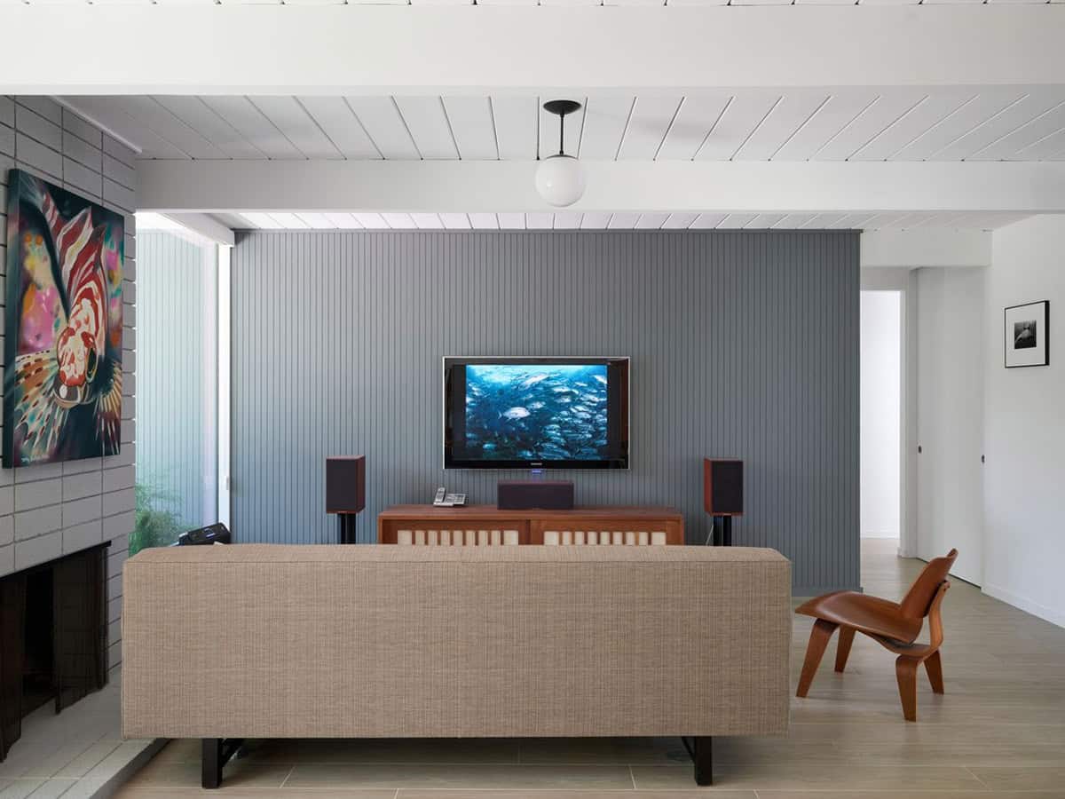 mid-century modern living room with gray accent wall fireplace Eames style lounge chair and underwater ocean photography on TV