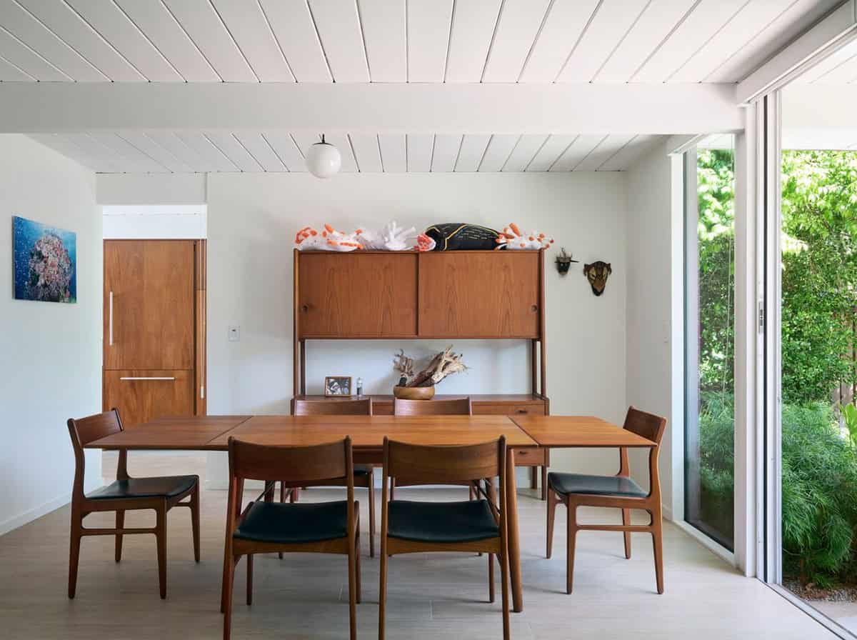 mid-century modern dining room with teak table and chairs walnut credenza sliding glass doors and ocean photography art