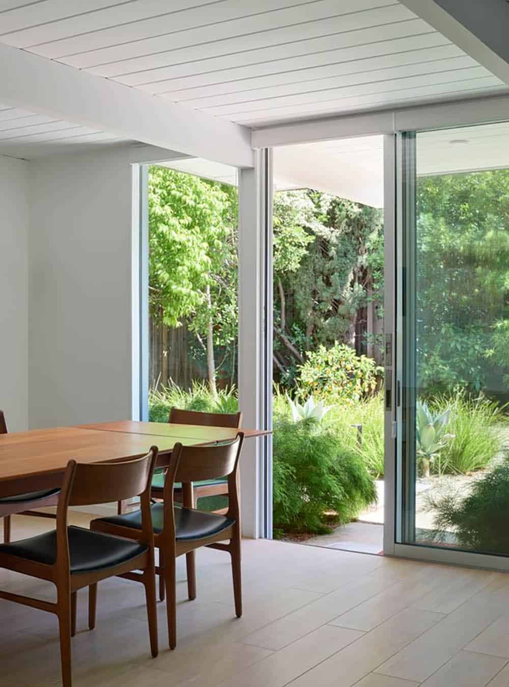 mid-century modern dining area with teak chairs and floor-to-ceiling sliding glass doors opening to lush garden Sunnyvale