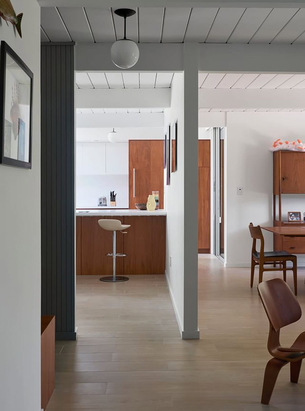 open plan Eichler interior hallway connecting renovated kitchen dining and living spaces with original beam ceiling