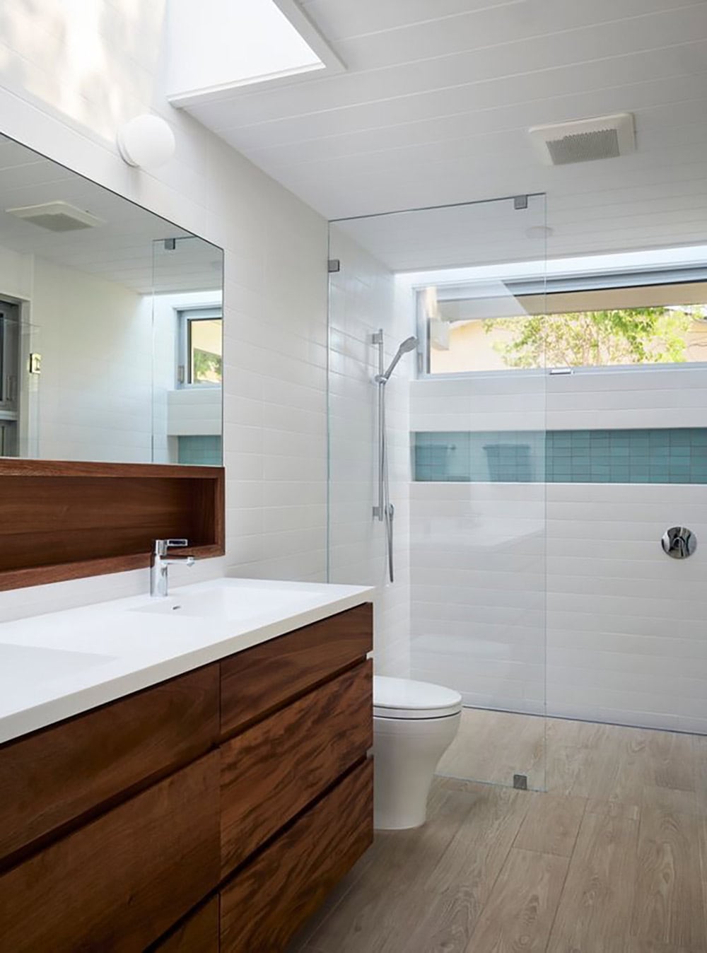 renovated Eichler bathroom with walnut vanity white countertop frameless glass shower and aqua tile accent strip