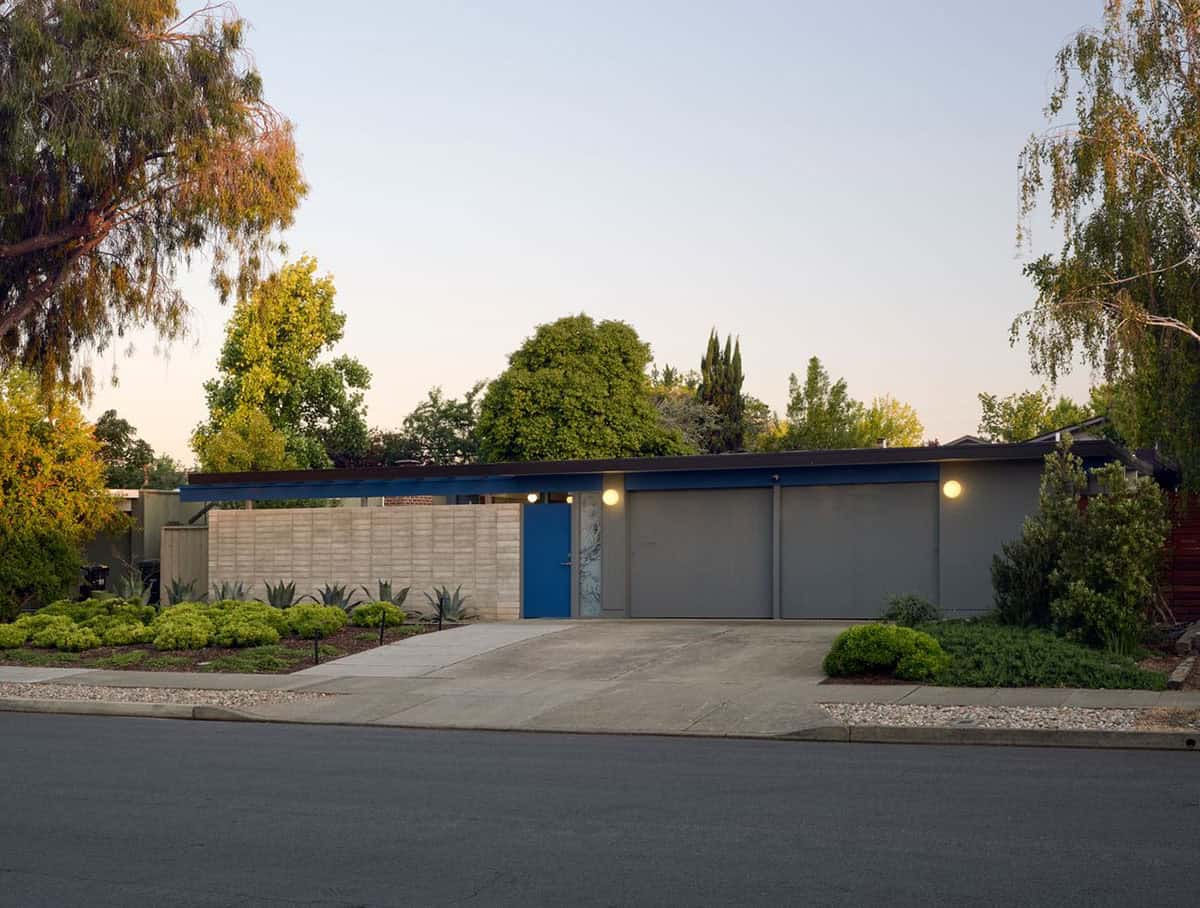mid-century modern Eichler home street view at dusk with blue front door globe lights concrete block wall and agave landscaping Sunnyvale California