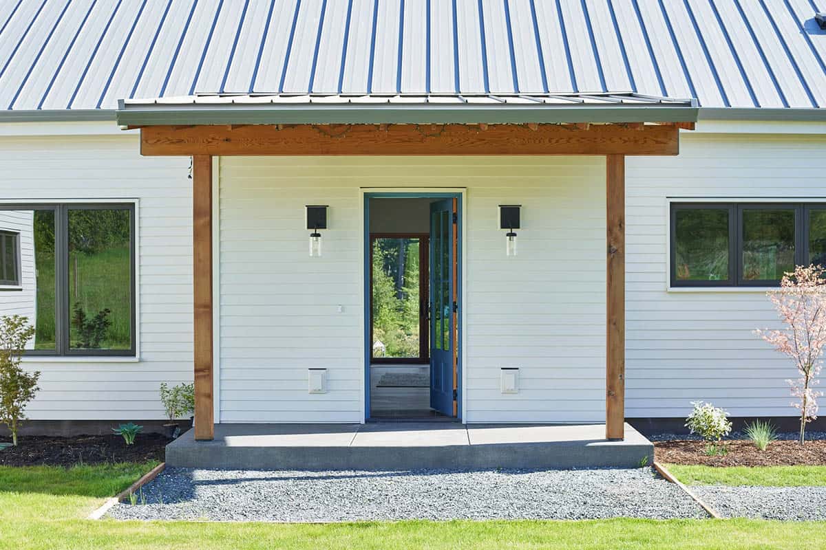 Covered front entry and door of the NorthShore Residence framed by warm wood detailing and lush Pacific Northwest plantings