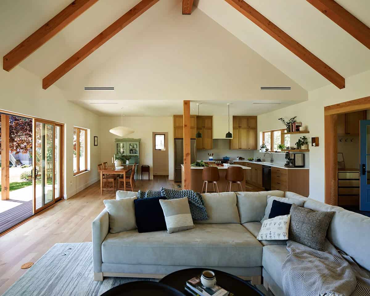 Panoramic view of the NorthShore Residence living room showing open layout, natural materials, and floor-to-ceiling windows with forest views