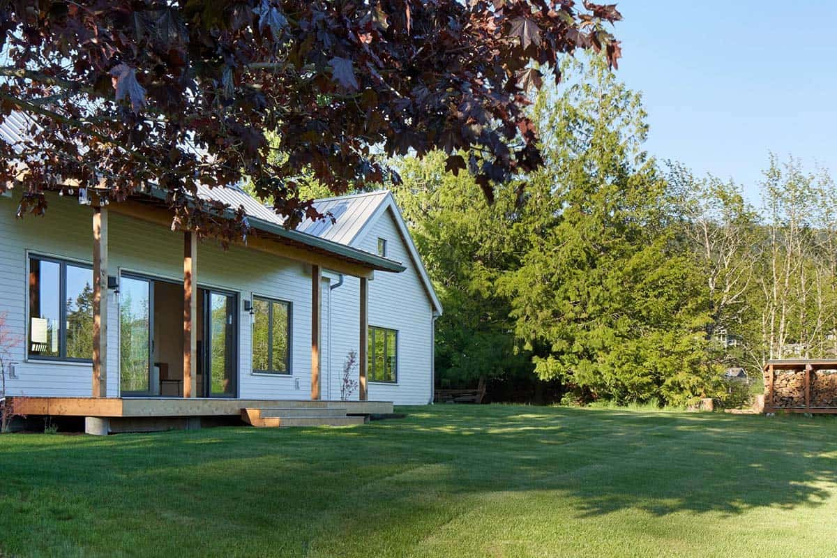 Exterior view of the NorthShore Residence with mature Pacific Northwest tree in the foreground and clean farmhouse facade