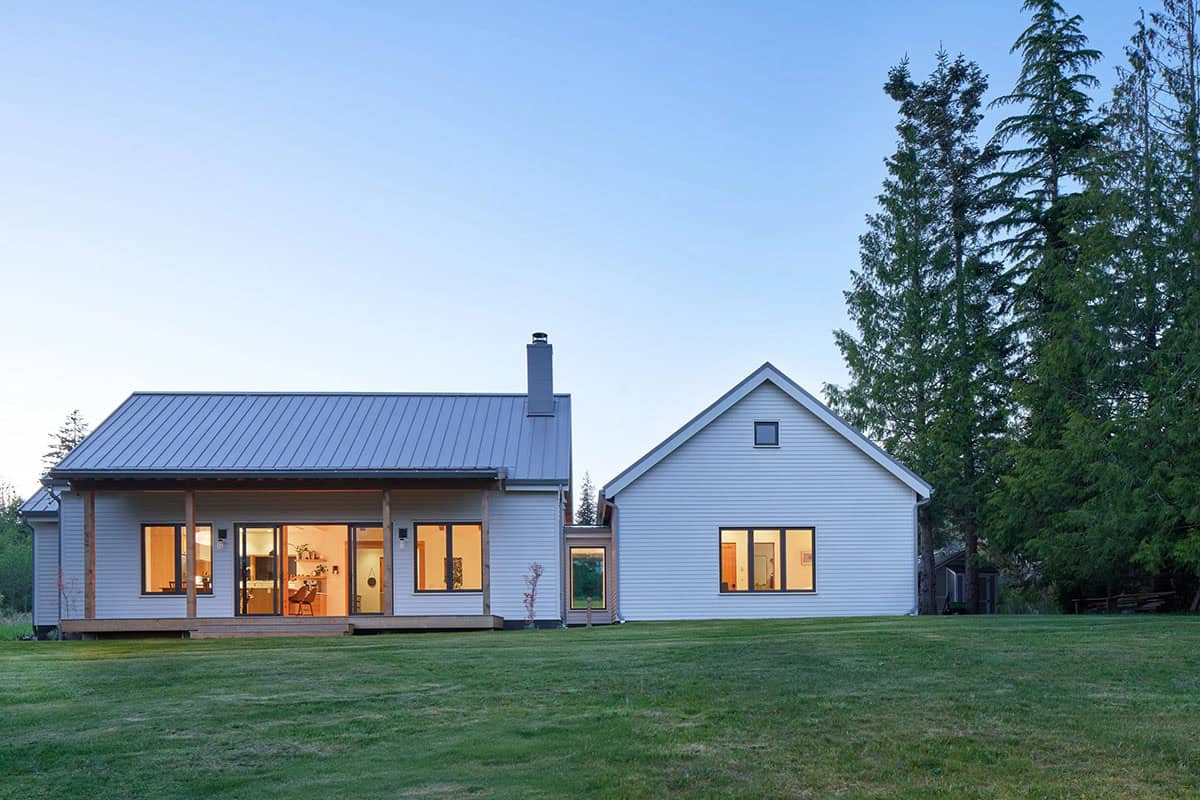 Dusk exterior view of the west facade with warm interior light glowing through generous windows