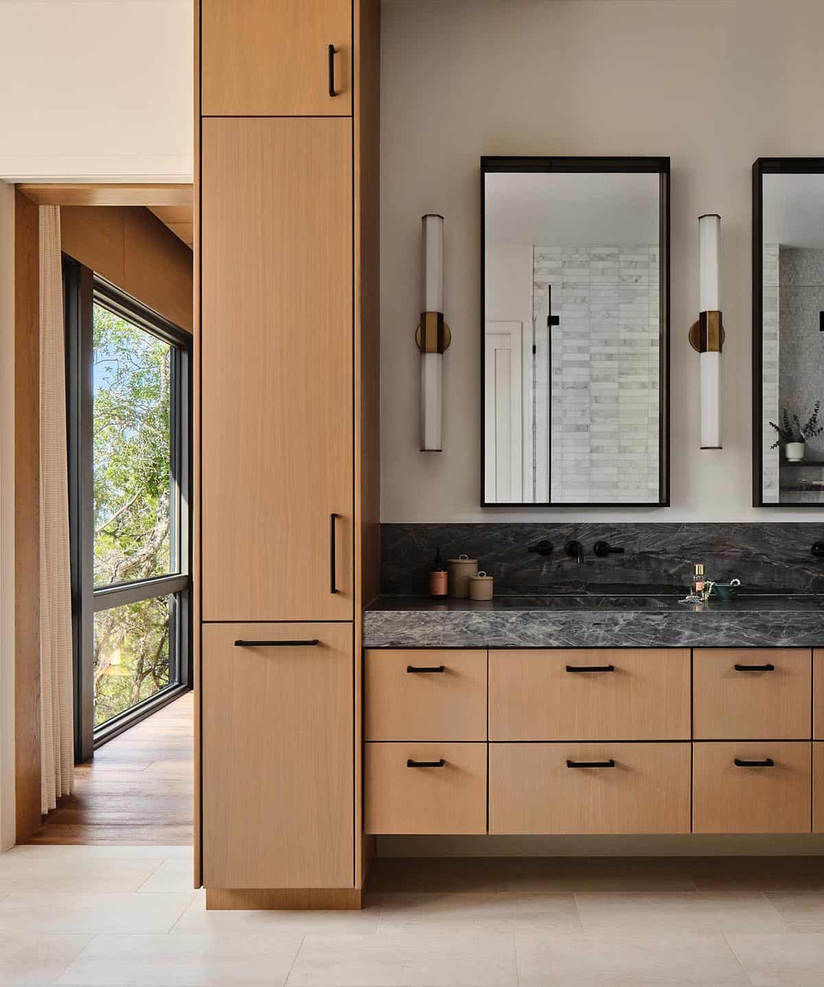 modern bathroom with light wood cabinets and a dark countertop