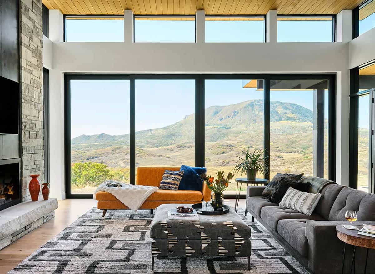 living room with oversized windows framing mountain views glass door closed