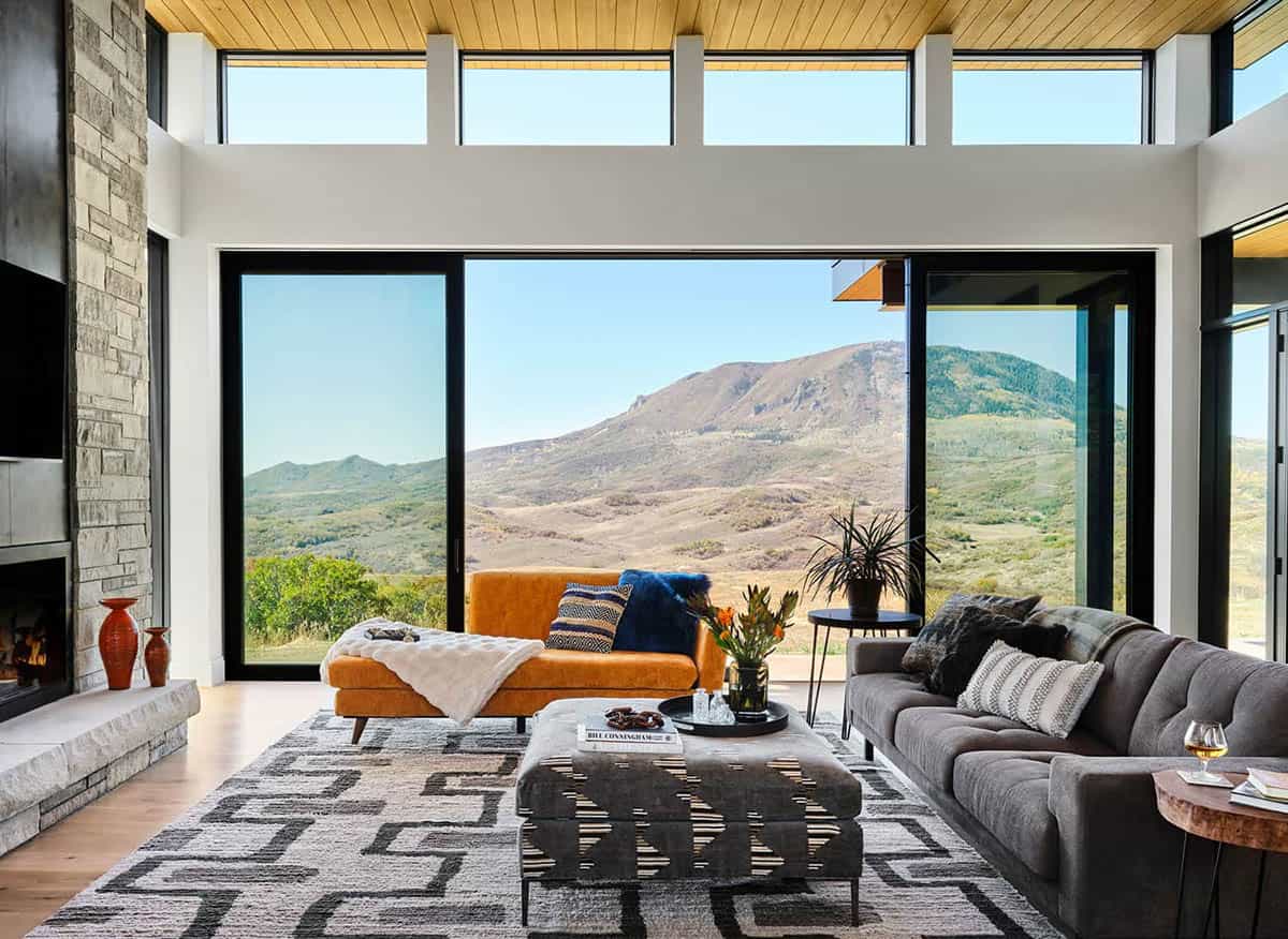 living room with pocketing glass doors open to outdoor deck and mountain landscape