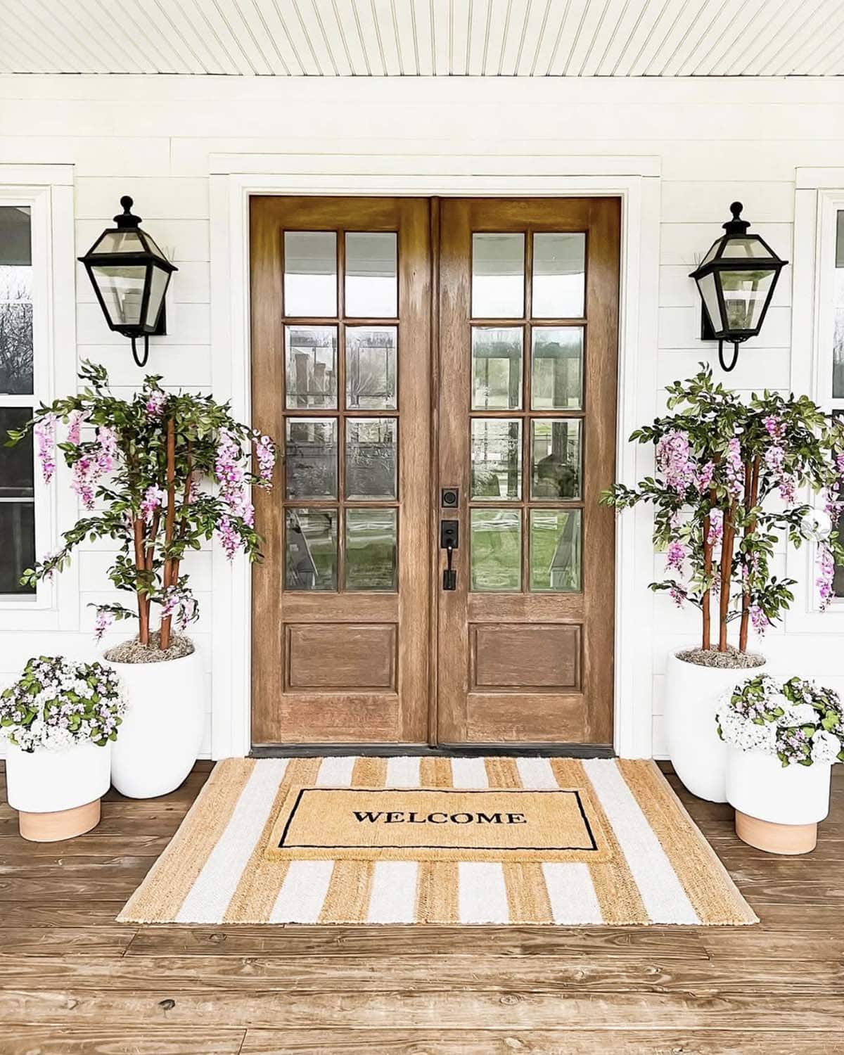 front porch decor with a welcome mat and potted wisteria trees