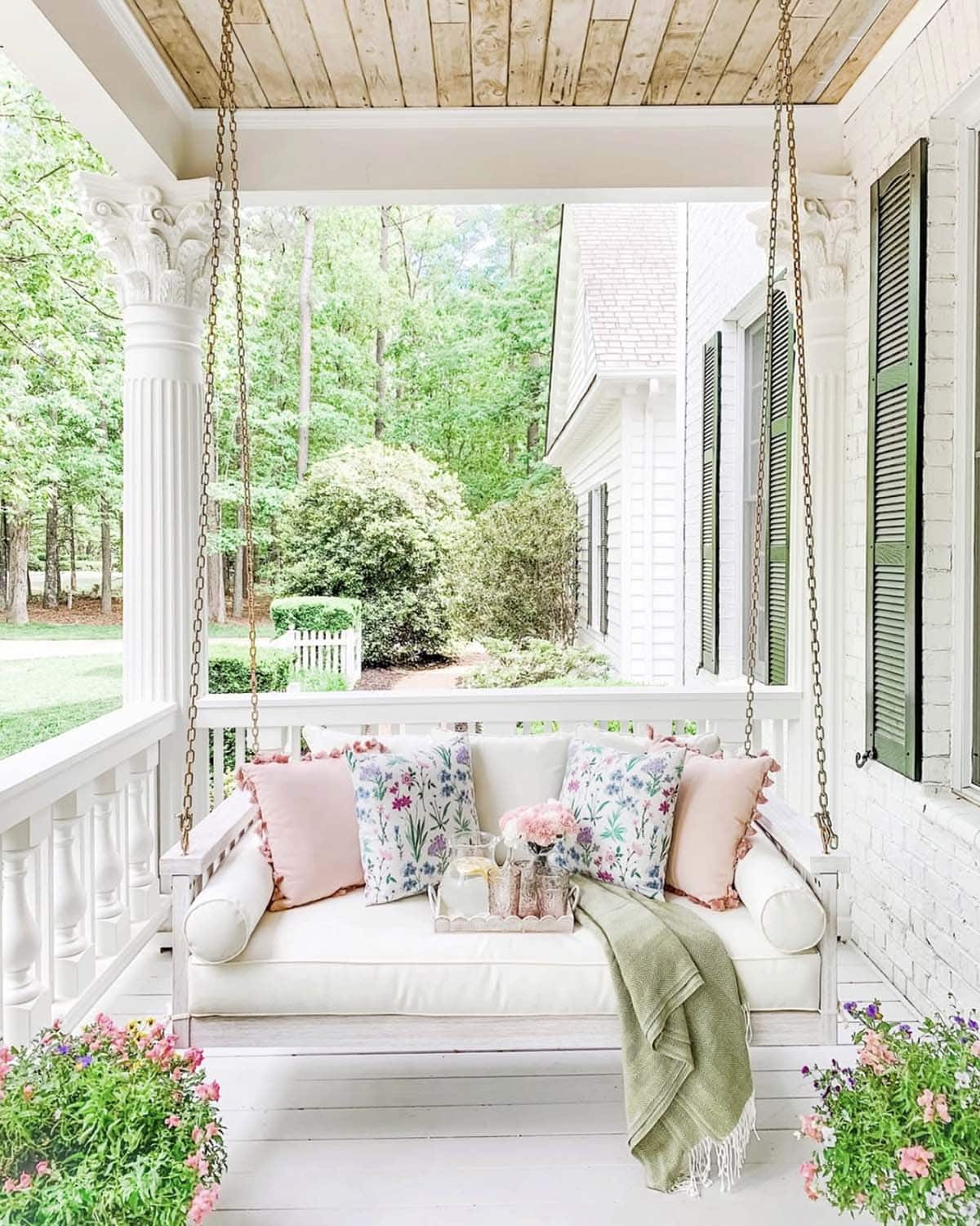 spring front porch with a hanging daybed and colorful pillows