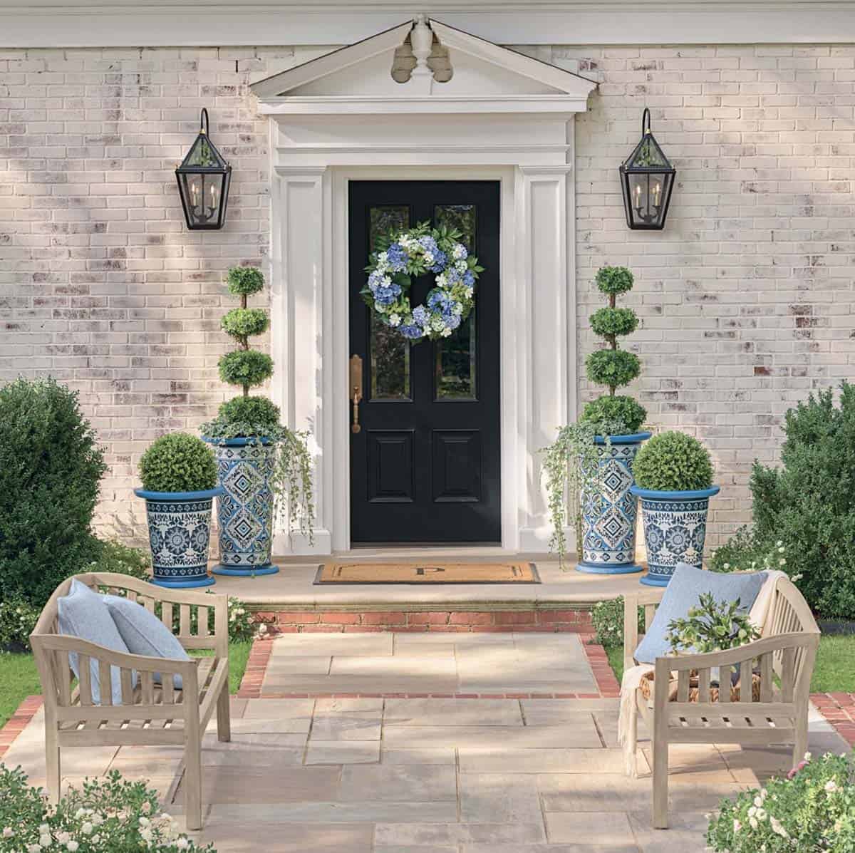 front porch with spring decorations including topiaries and a door wreath