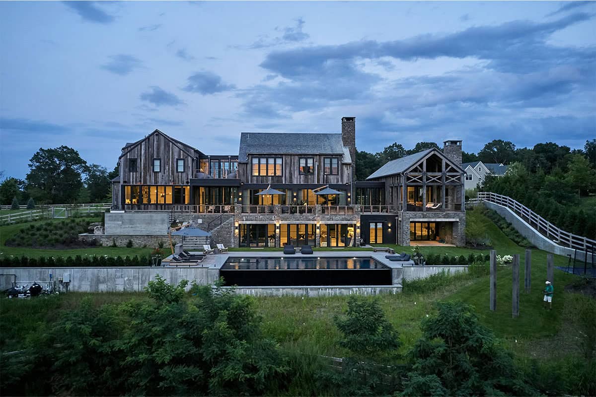 rustic modern barn house exterior with a pool at dusk