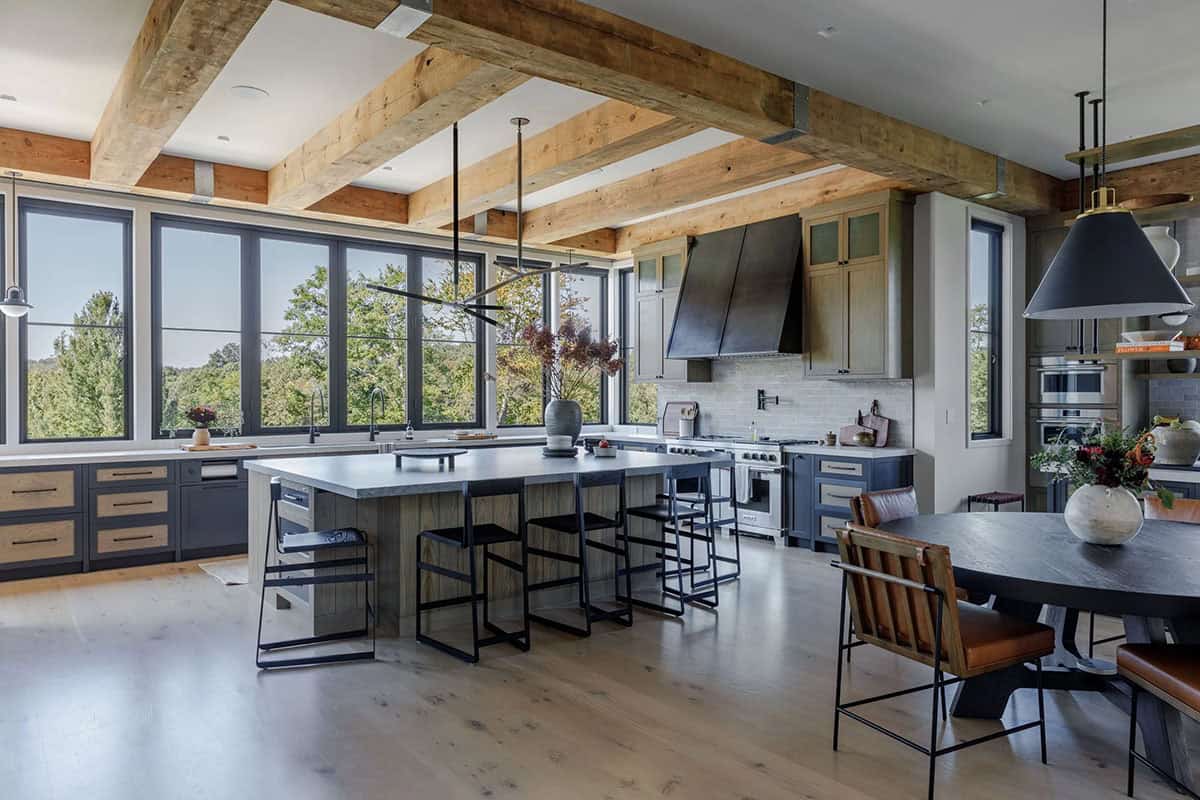 Spacious kitchen featuring large windows, wooden beams, and contemporary cabinetry