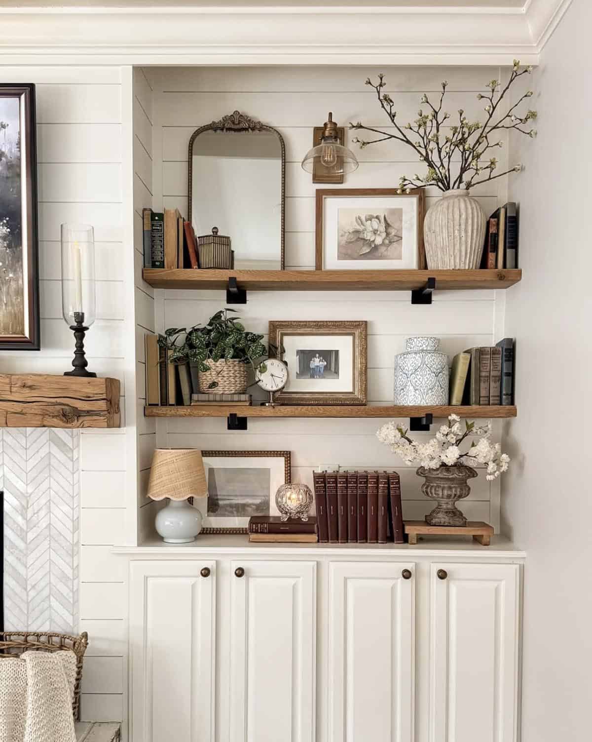 Spring decorating ideas for bookshelves with cherry blossom branches, botanical art, and layered decor on white shiplap shelves