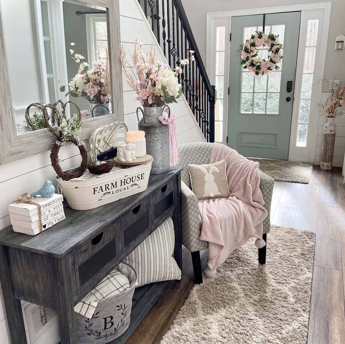 Spring farmhouse entryway with cherry blossom stems, bunny wreath, pink floral front door wreath, and bunny pillow