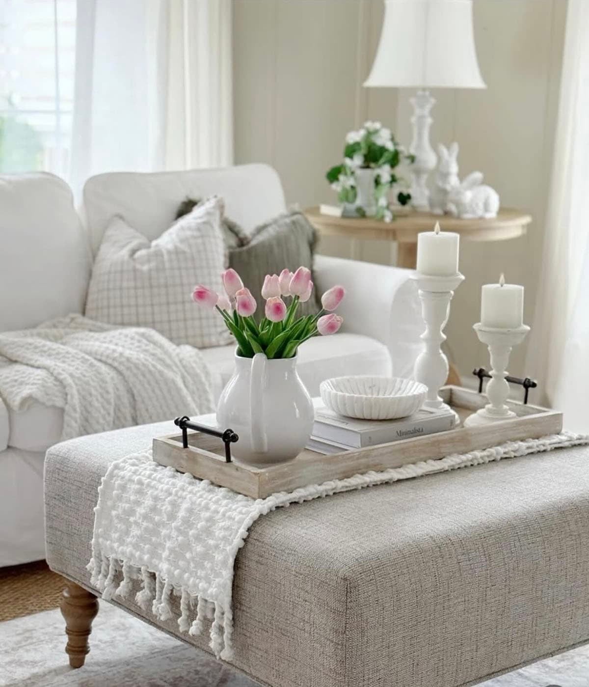 Spring ottoman tray styling with pink tulips, white candles, and ceramic dish in neutral living room