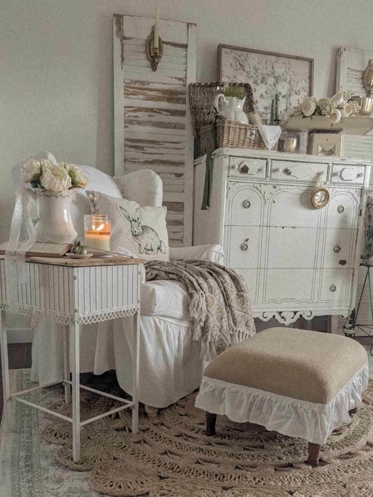 Shabby chic spring reading nook with bunny pillow, white slipcovered chair and vintage dresser