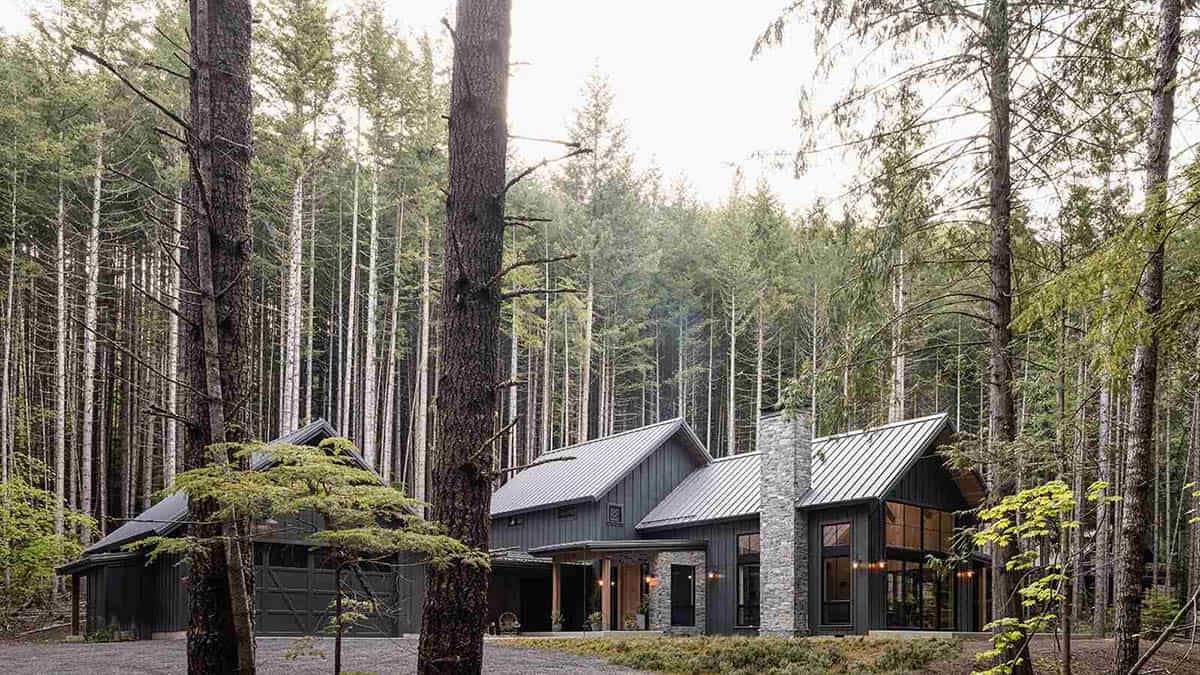 Aerial view of alpine cabin with metal roof surrounded by tall pine forest, Greenwater, Washington